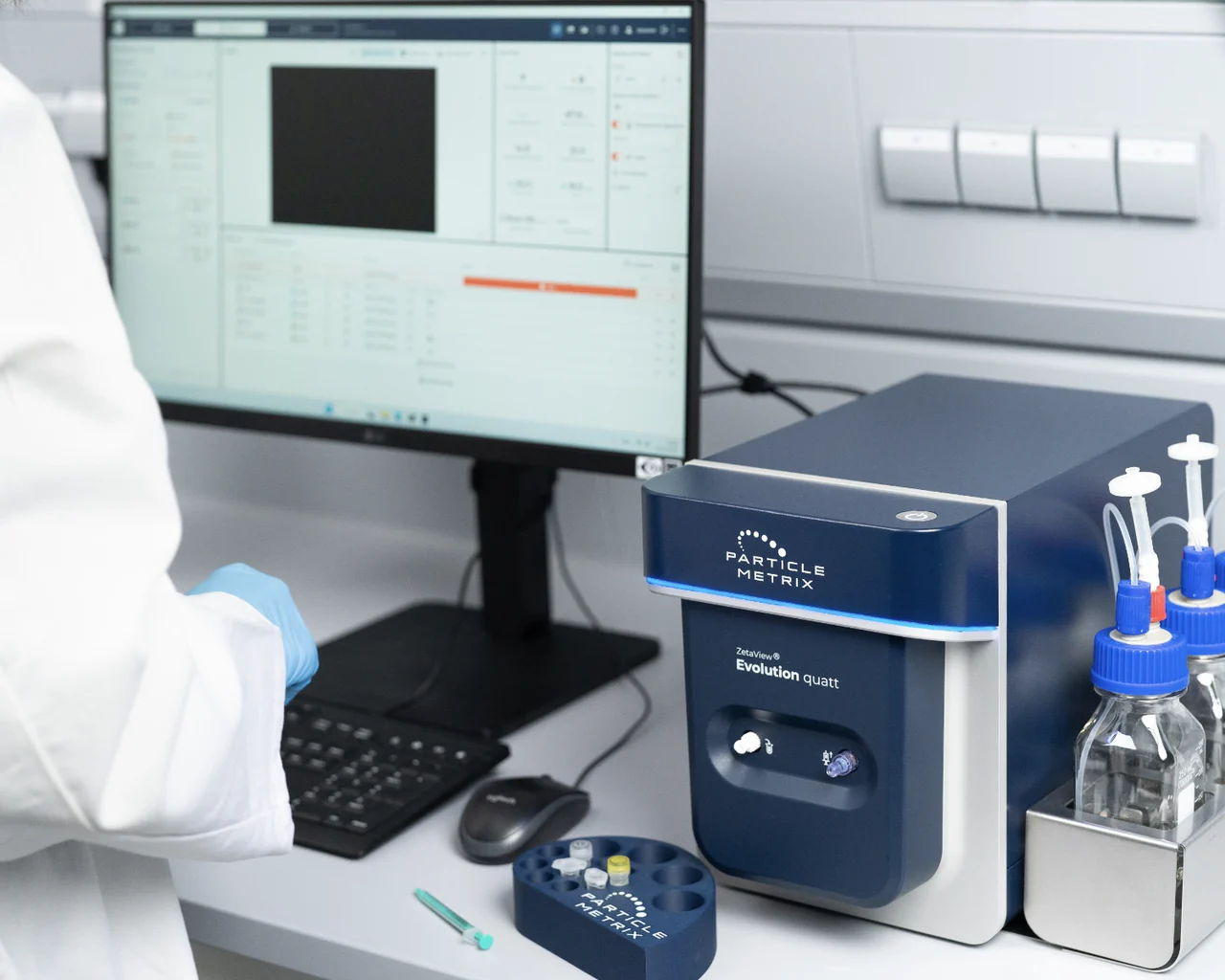 ZetaView Evolution Quatt on a laboratory bench beside a monitor running ZetaSphere software, with sample vials and buffer bottles